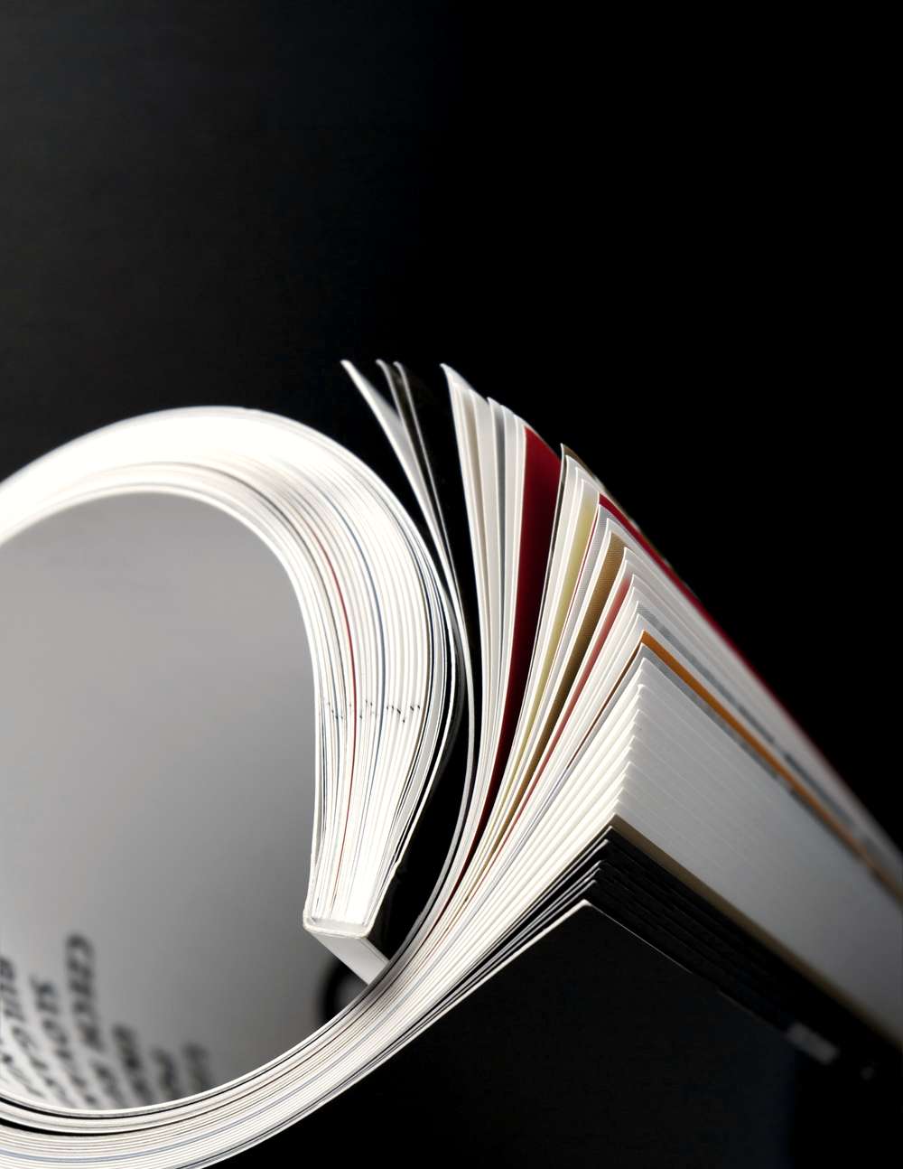 Páginas de un libro abriéndose como un abanico, sobre fondo negro