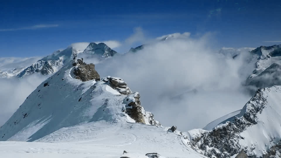 Cumbres nevadas sobre un mar de nubes, vistas desde una cresta