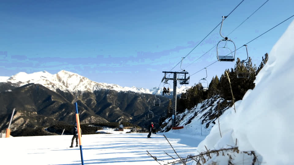 Una pista de esquí con un telesilla y la cordillera al fondo