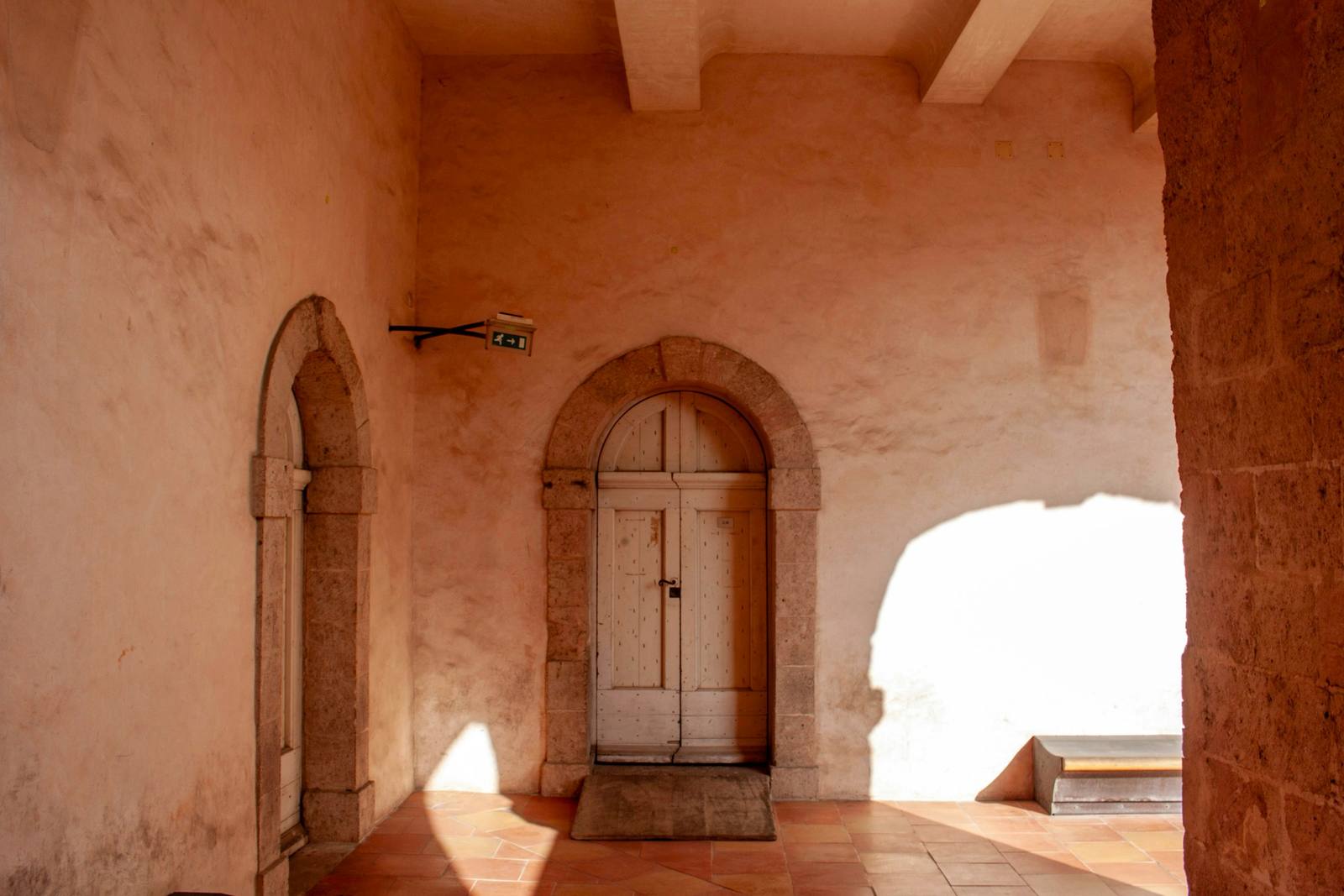 Pórtico de cal rosada con una puerta de madera bajo un arco