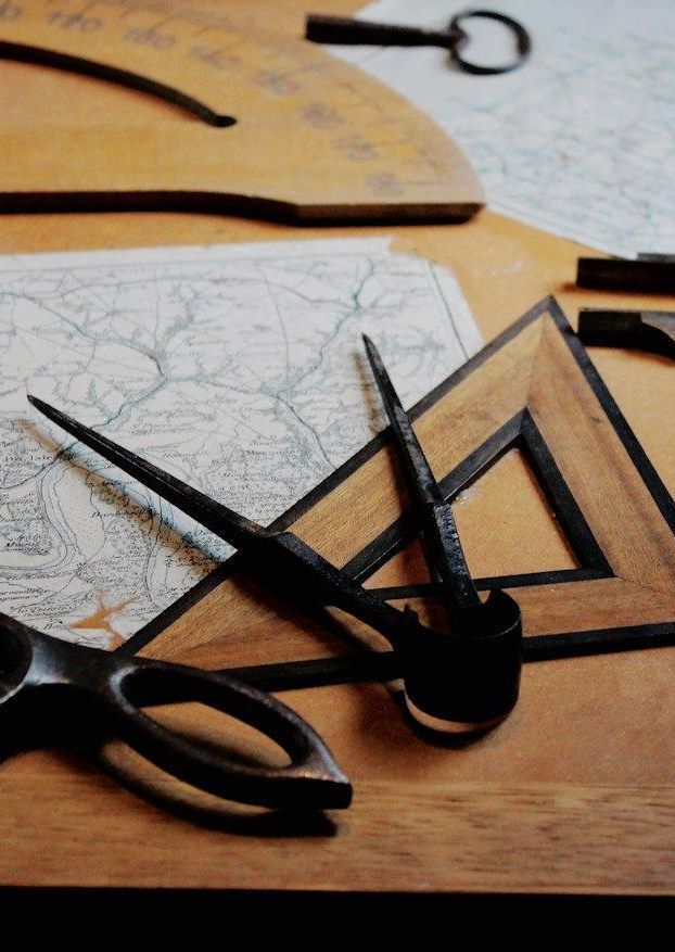 Compases, escuadras y tijeras de sastre sobre un tablero de madera