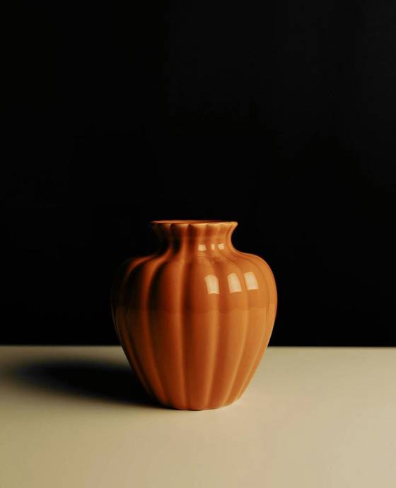 Jarrón acanalado de color terracota sobre un fondo negro