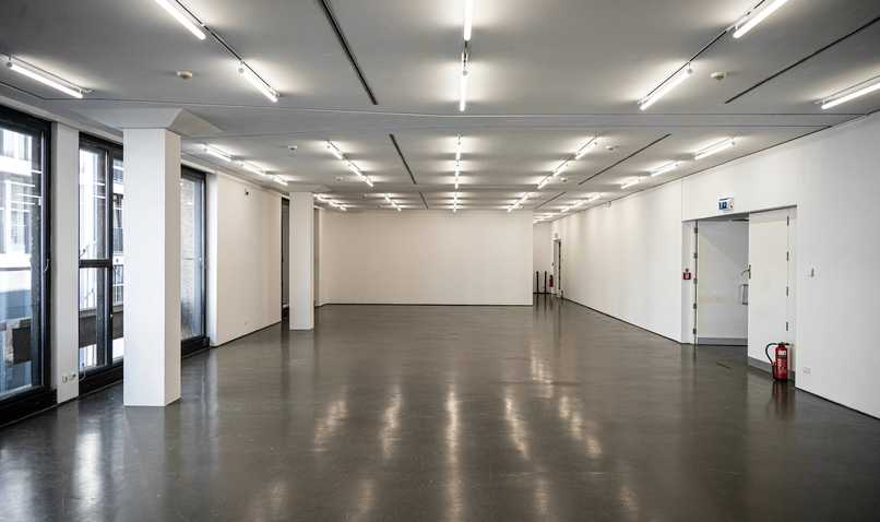 Sala de exposición vacía, con luces en el techo y suelo pulido