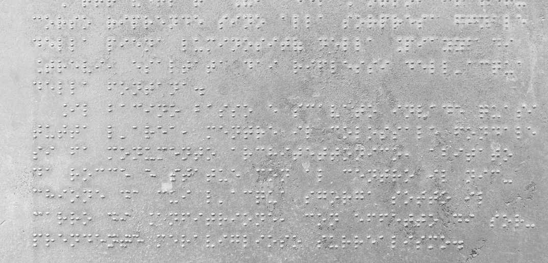 Texto en braille grabado sobre una superficie gris