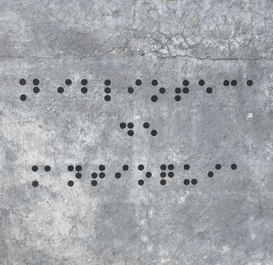 Puntos de braille pintados sobre concreto gris