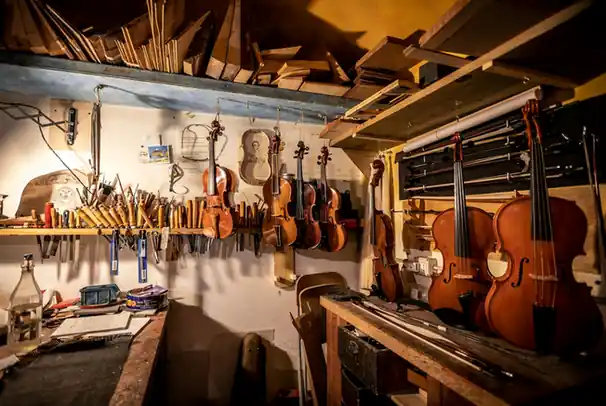 Taller con violines colgados de la pared y un banco de trabajo