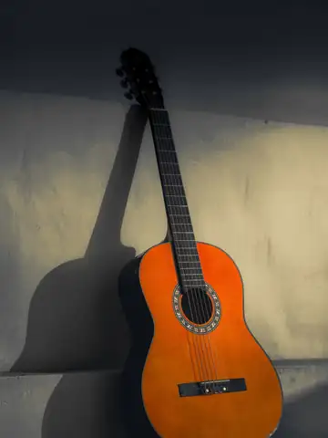 Guitarra clásica apoyada en una pared, con su sombra