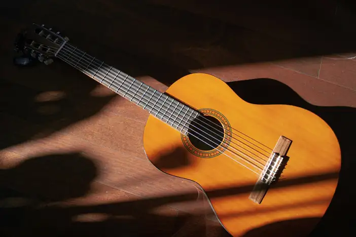 Guitarra clásica sobre el suelo, con rayos de sol