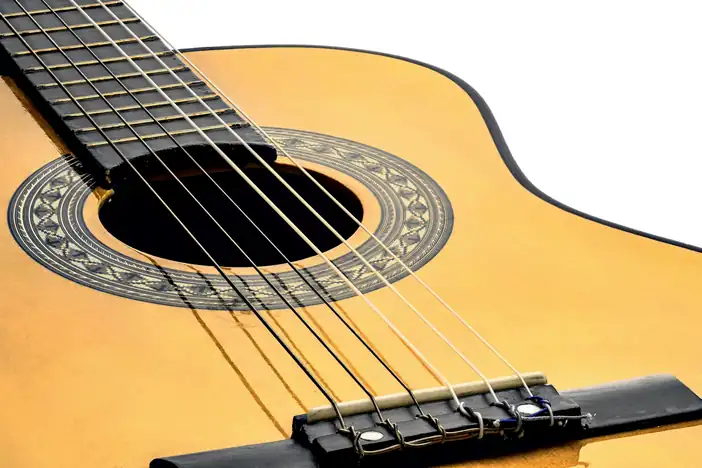 Guitarra de tapa clara con su rosetón, sobre un fondo blanco