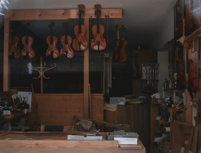 Taller con violines colgados y un banco de trabajo